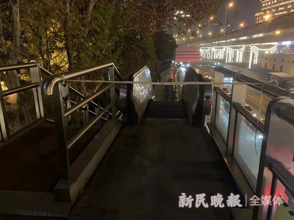人行天桥东侧的一处电梯出口处被人用隔离带拦起，电梯处于停止运行的状态.jpg