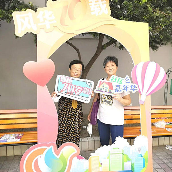 居民们手举各式对曹杨的祝福语在设计精美的相框前合影留念,在摄影师